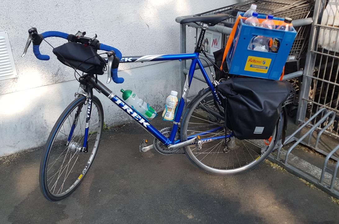 Trek before the Edeka Lajos store in Reinheim, carrying two pannier bags and a bottle crate with empty bottles.